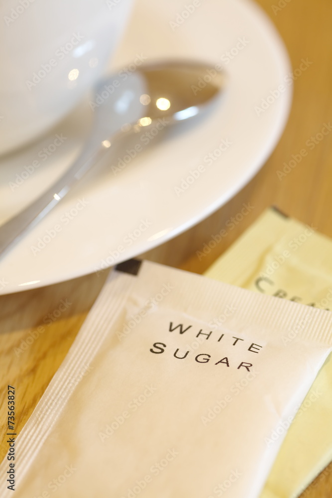 一杯咖啡旁边的白糖纸袋