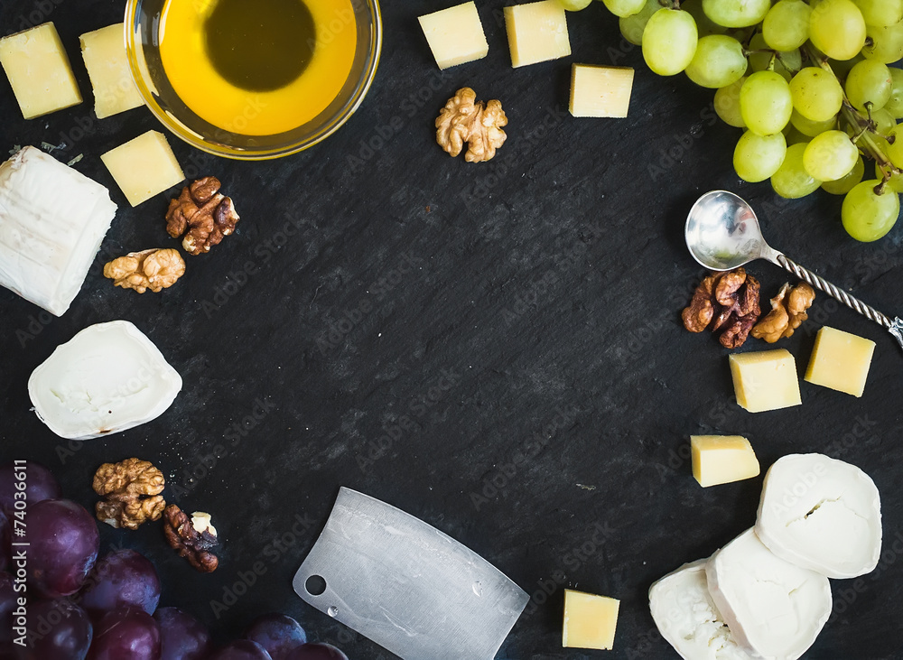 Cheese selection with fresh grapes, walnuts and honey on a dark