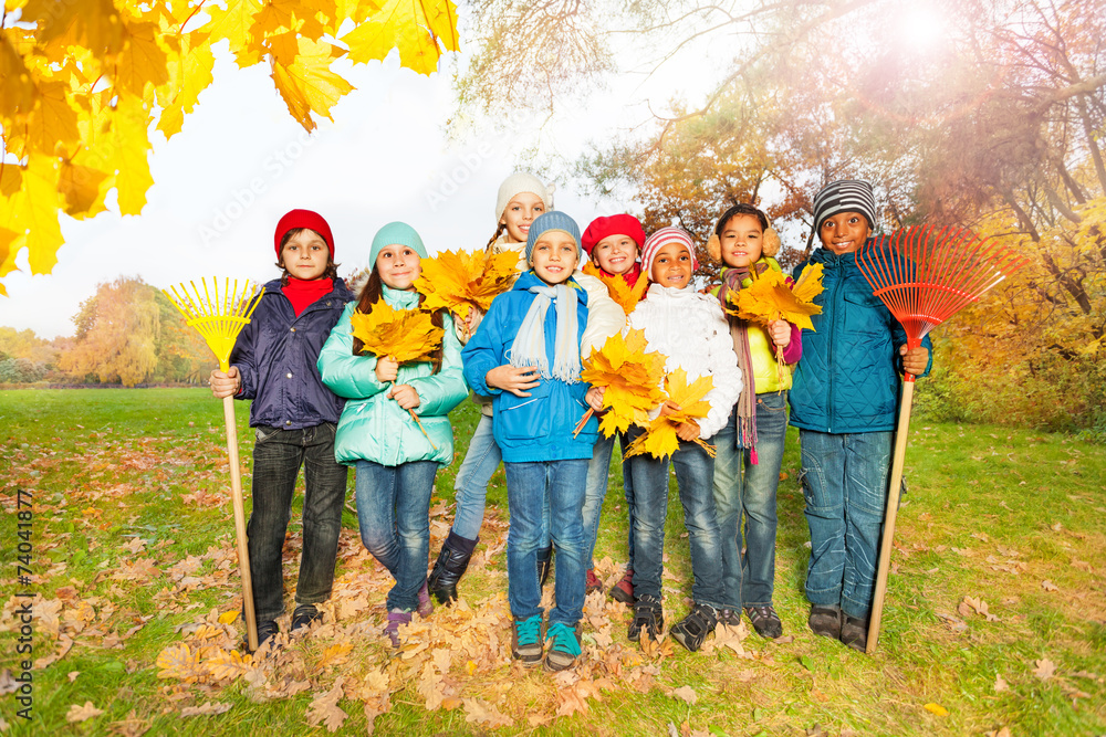 一群快乐的孩子，带着耙子和树叶