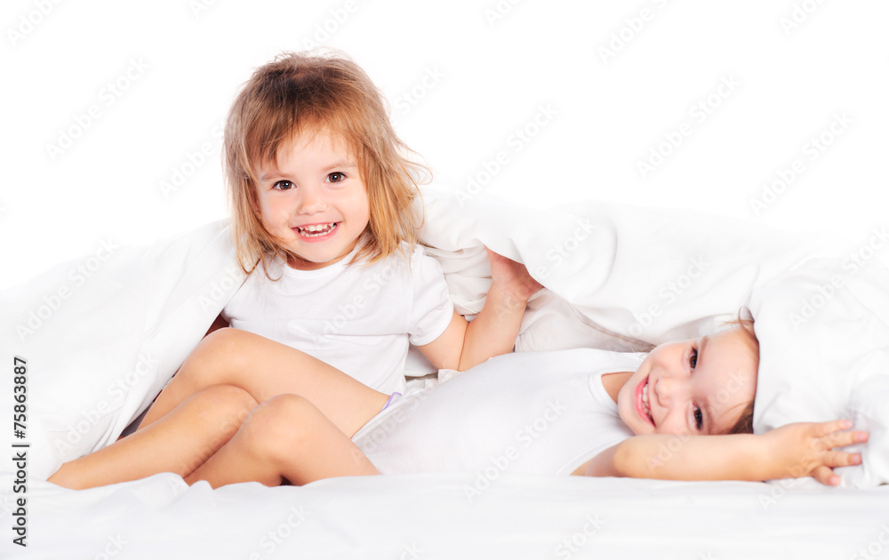 happy little girls twins sister in bed having fun