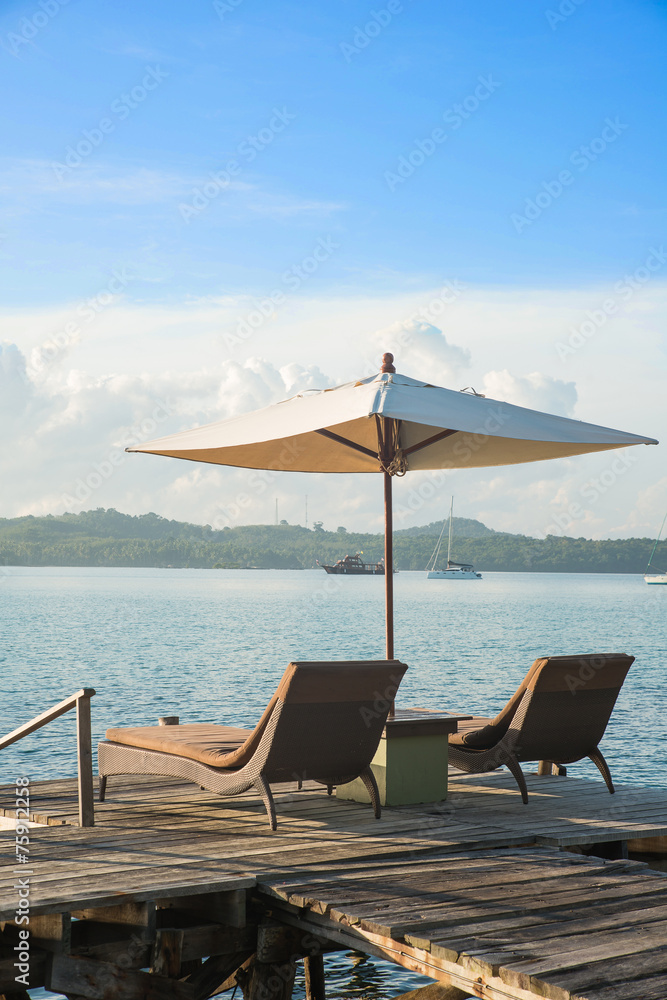 普吉岛度假酒店木桌上的两把椅子和雨伞