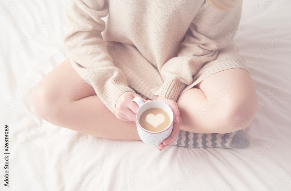 女孩的腿温暖的羊毛袜和一杯咖啡