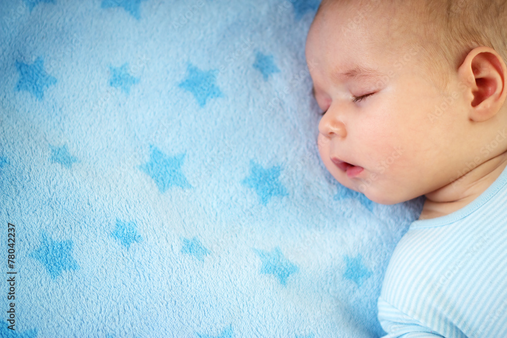 3个月大的婴儿睡在蓝色毯子上