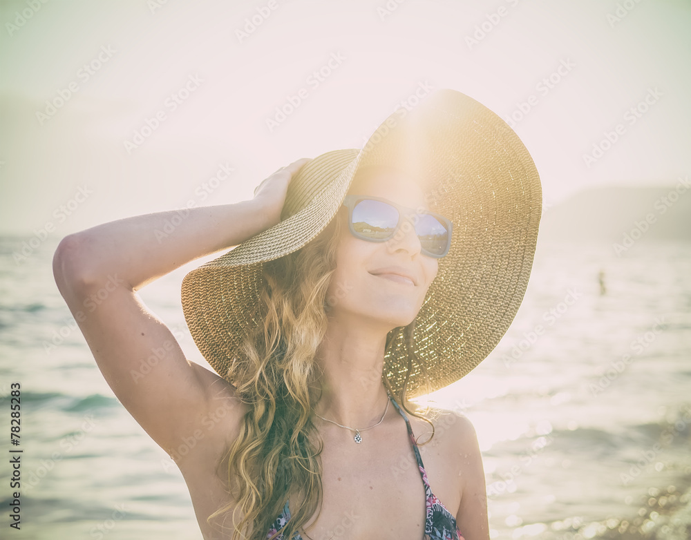 海滩上戴着墨镜和草帽的年轻金发女孩