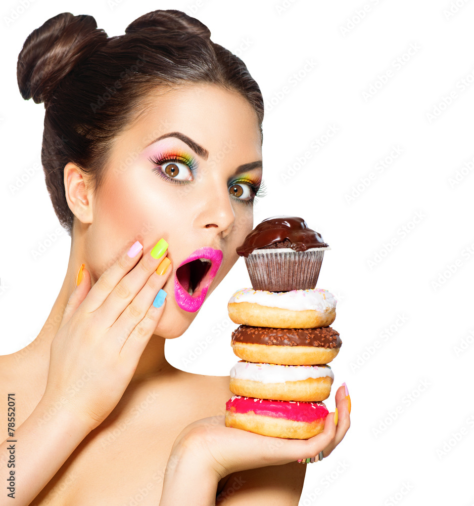 美女时尚模特女孩拿糖果和五颜六色的甜甜圈