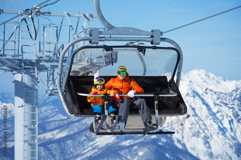 父亲和男孩坐在滑雪缆车上翻山越岭
