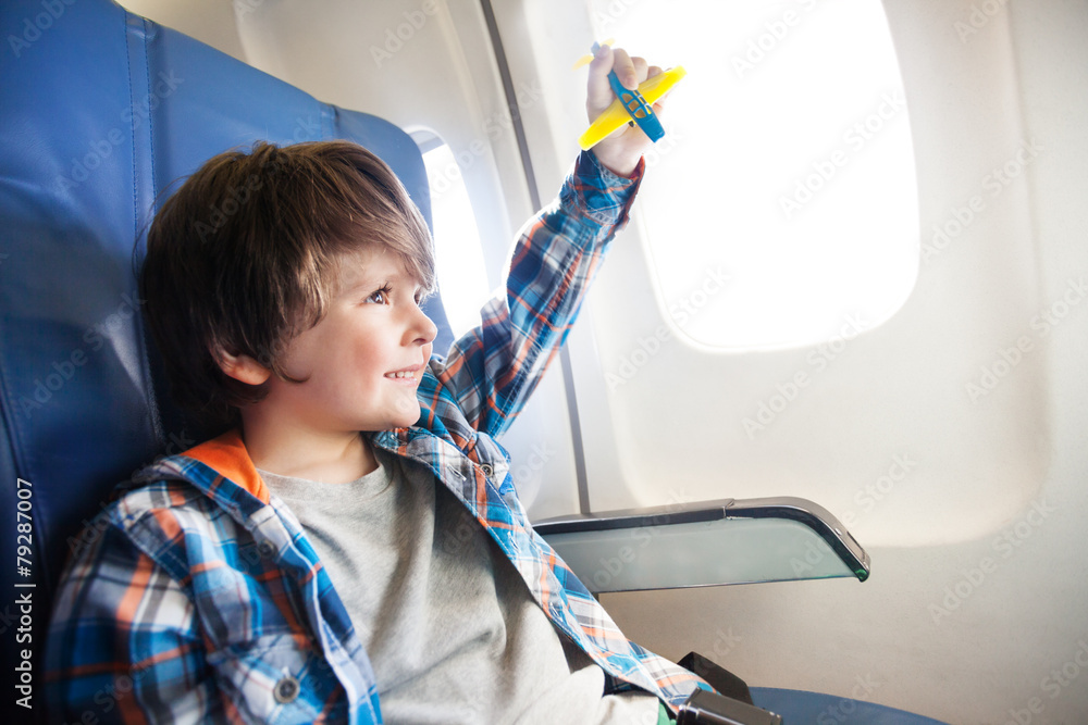 微笑的小男孩，窗户边拿着玩具飞机