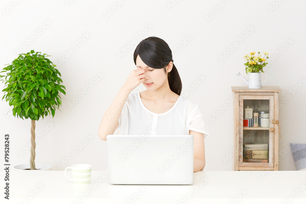 パソコンの前で目頭を押さえる女性