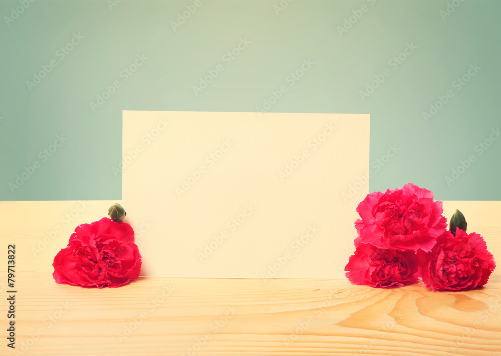 桌上摆着康乃馨花的空白贺卡