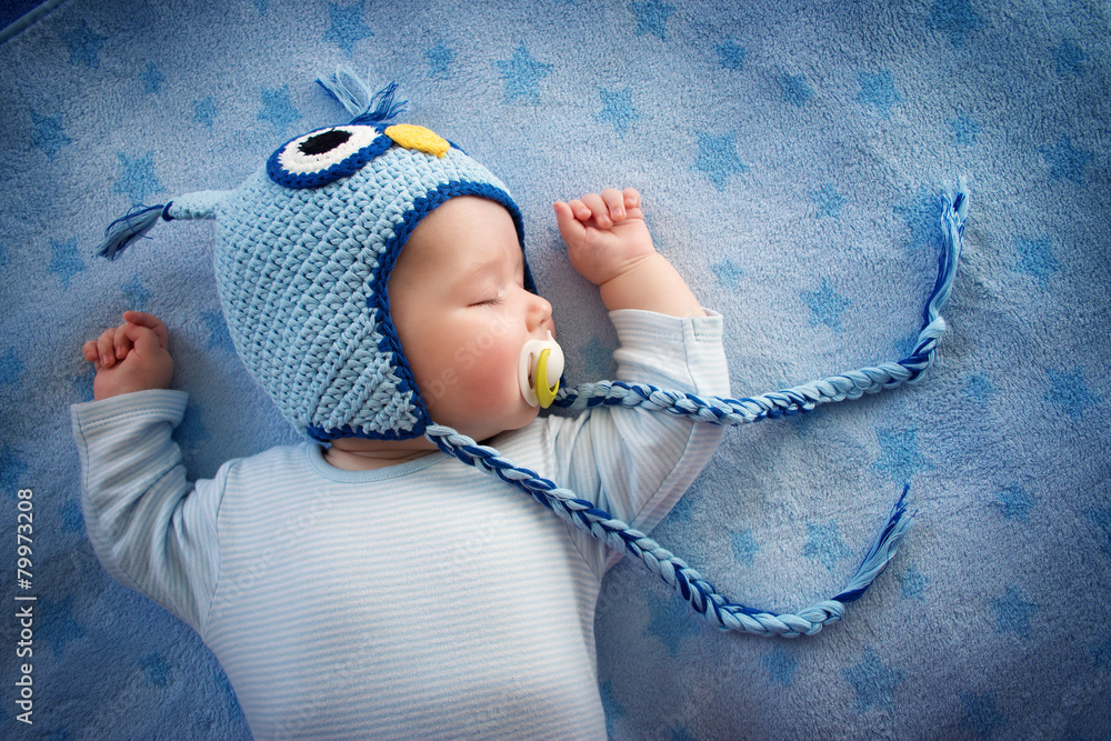 睡在蓝色毯子上的猫头鹰里的4个月大的婴儿