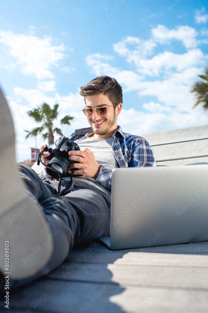 Young photographer with laptop and photo camera