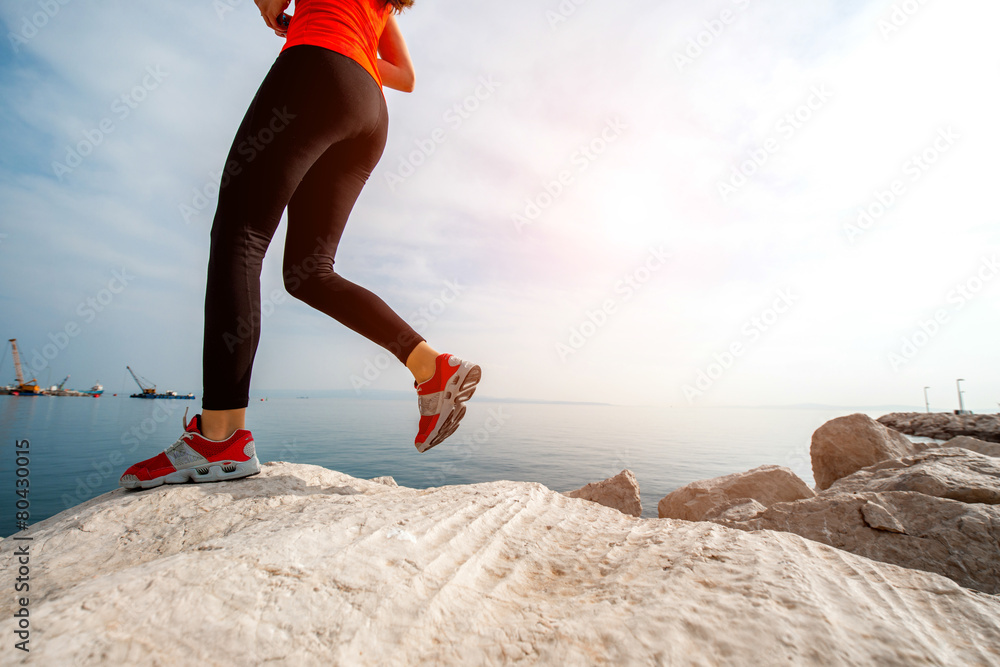 运动女性在岩石海滩上跑步