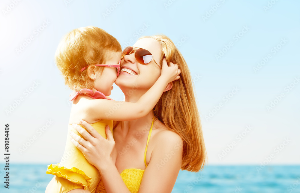 海滩上的幸福家庭。宝贝女儿亲吻母亲