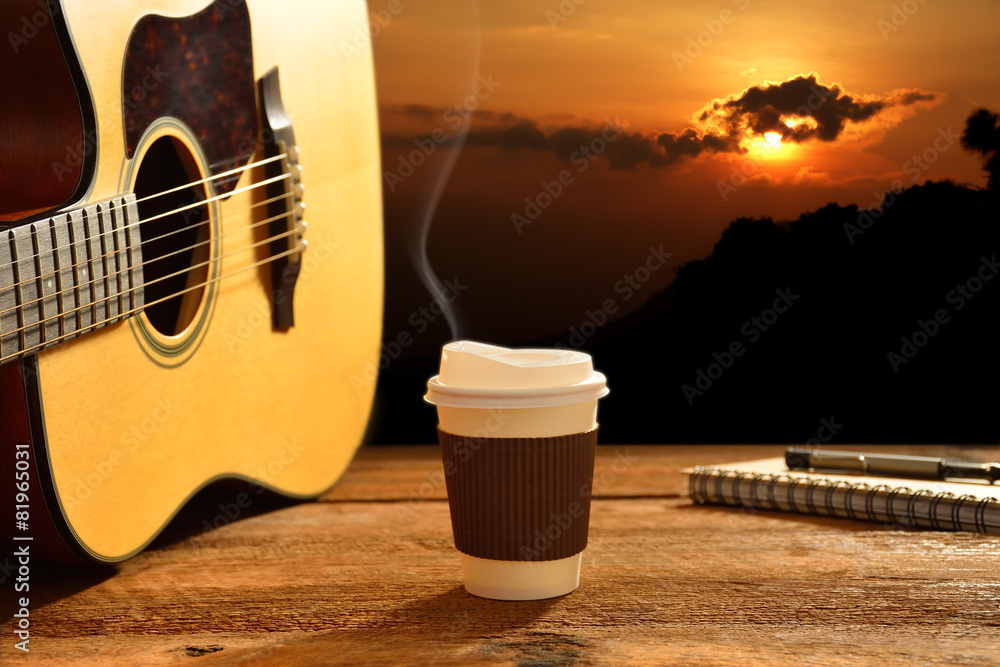 背景是阳光的纸杯咖啡和吉他