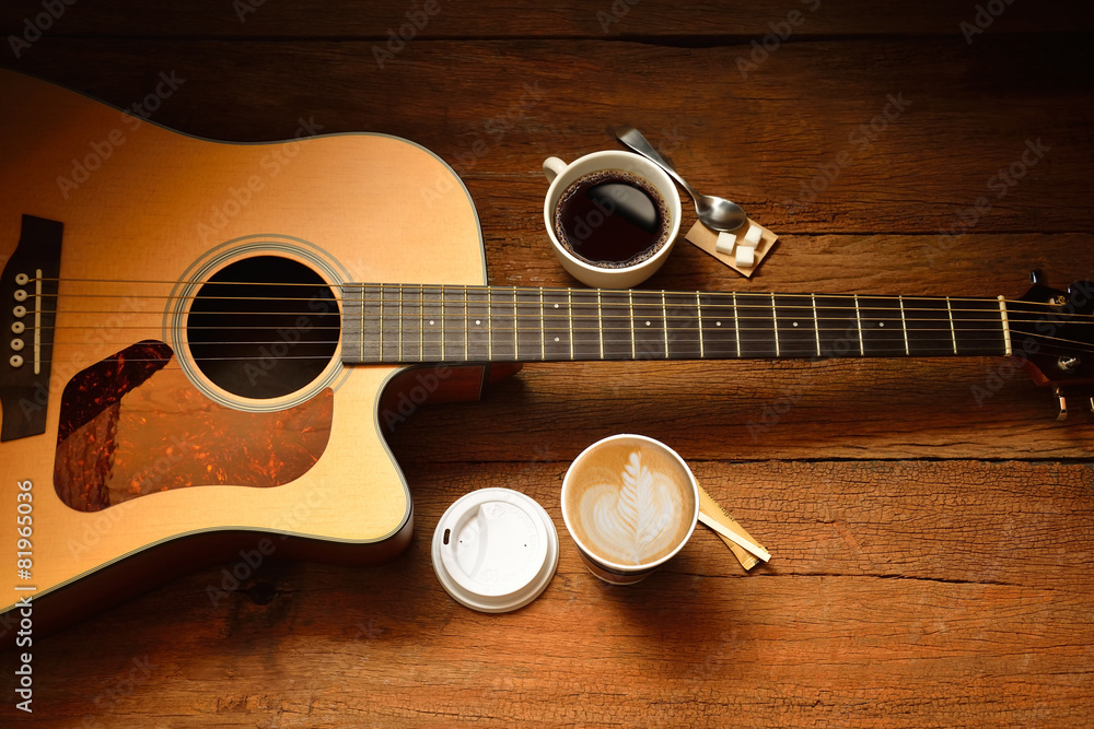 Cups of coffee and guitar on wooden table