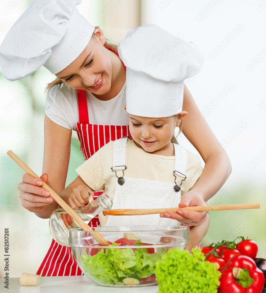 Food. Loving mother teaching little daughter mixing salad at