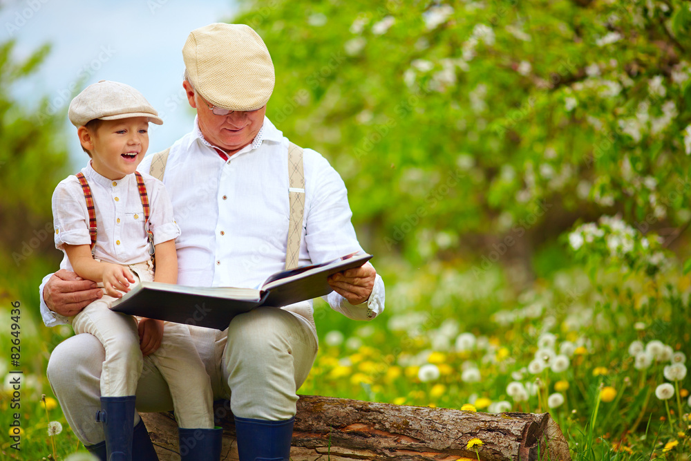 grandfather reading a book to his grandson, in blooming garden