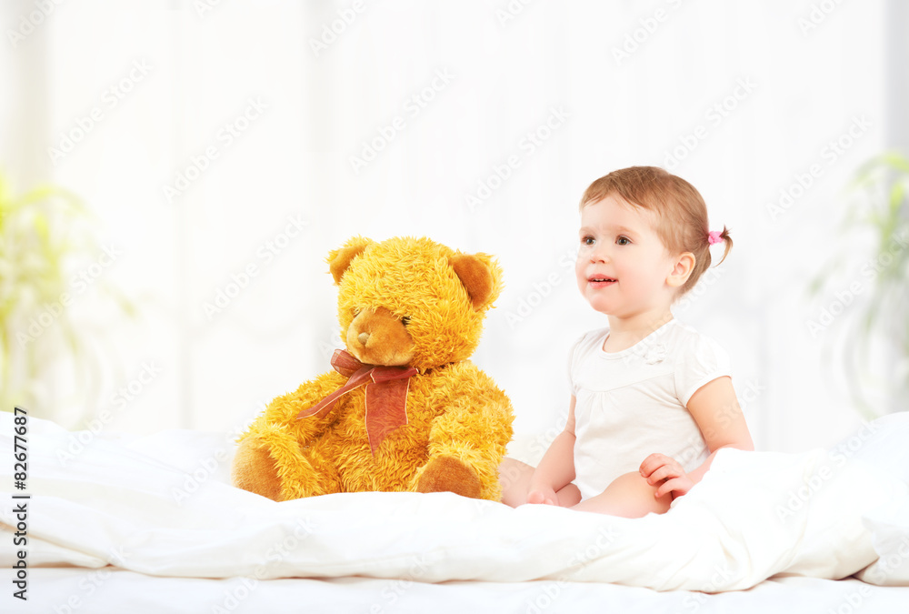 可爱的小女孩在床上拥抱泰迪熊