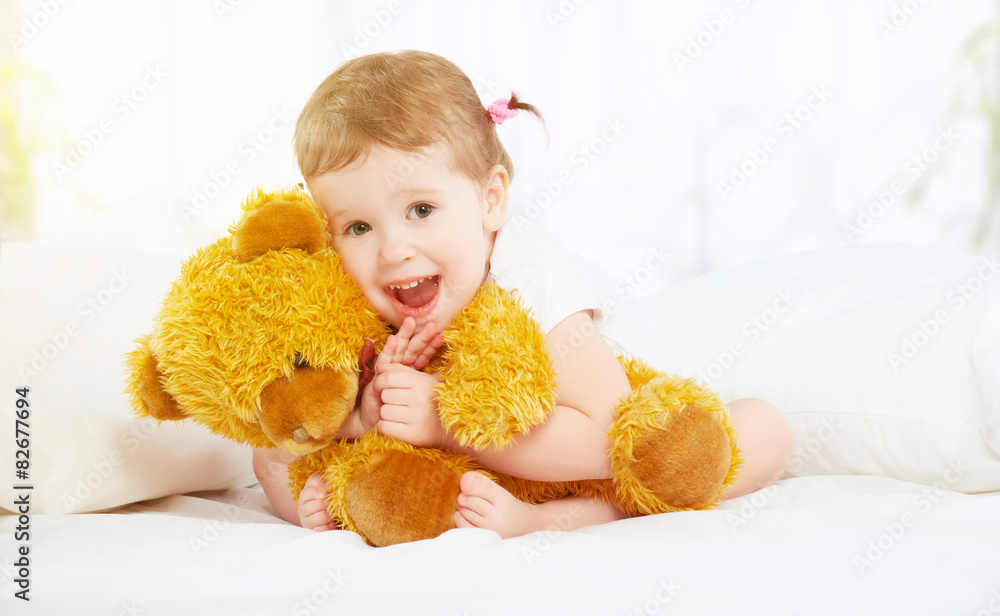 可爱的小女孩在床上拥抱泰迪熊