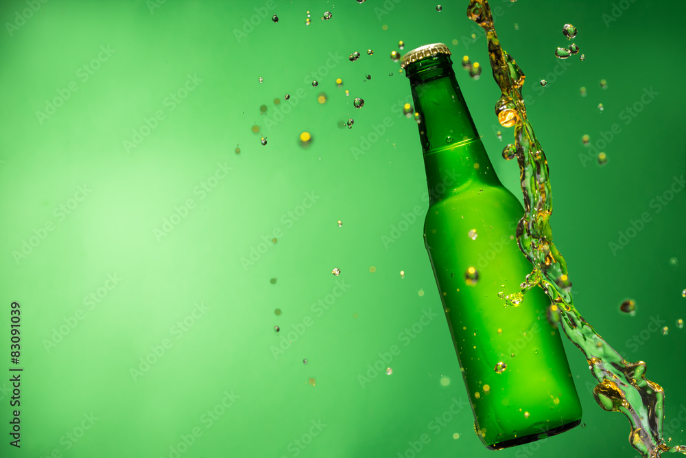 绿色背景上有飞溅物的啤酒瓶