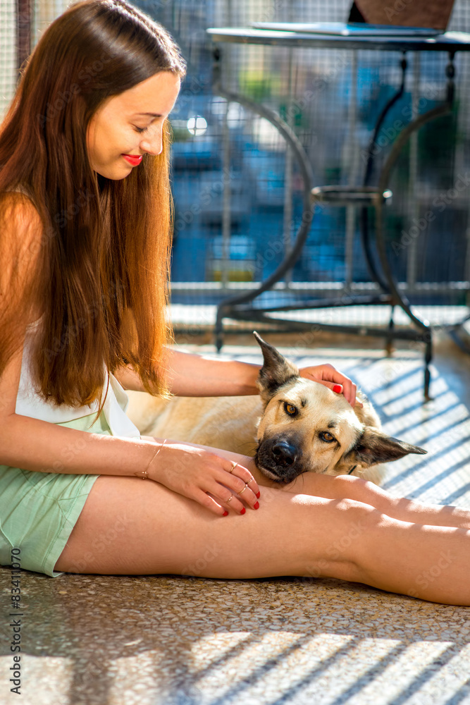 年轻女子带着她的狗在阳台上
