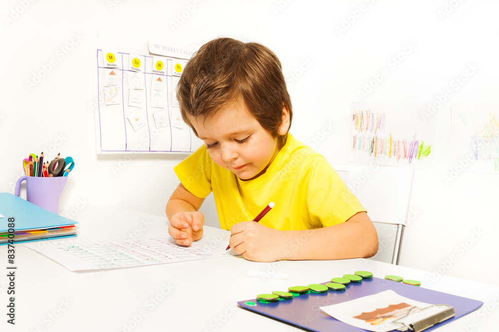 专心的小男孩独自用铅笔写字