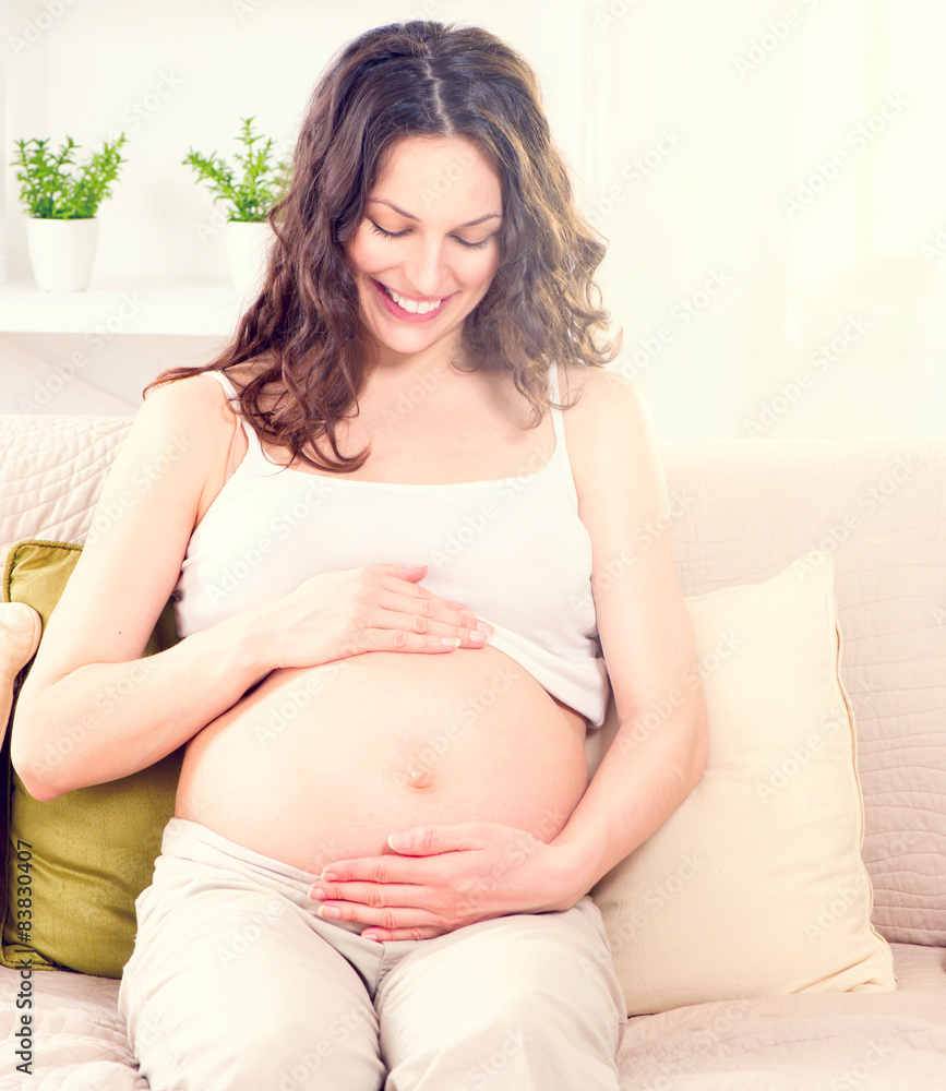 孕妇坐在沙发上抚摸自己的肚子