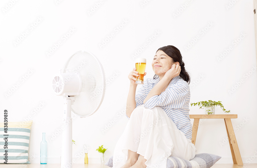 扇風機にあたりながらビールを飲む女性