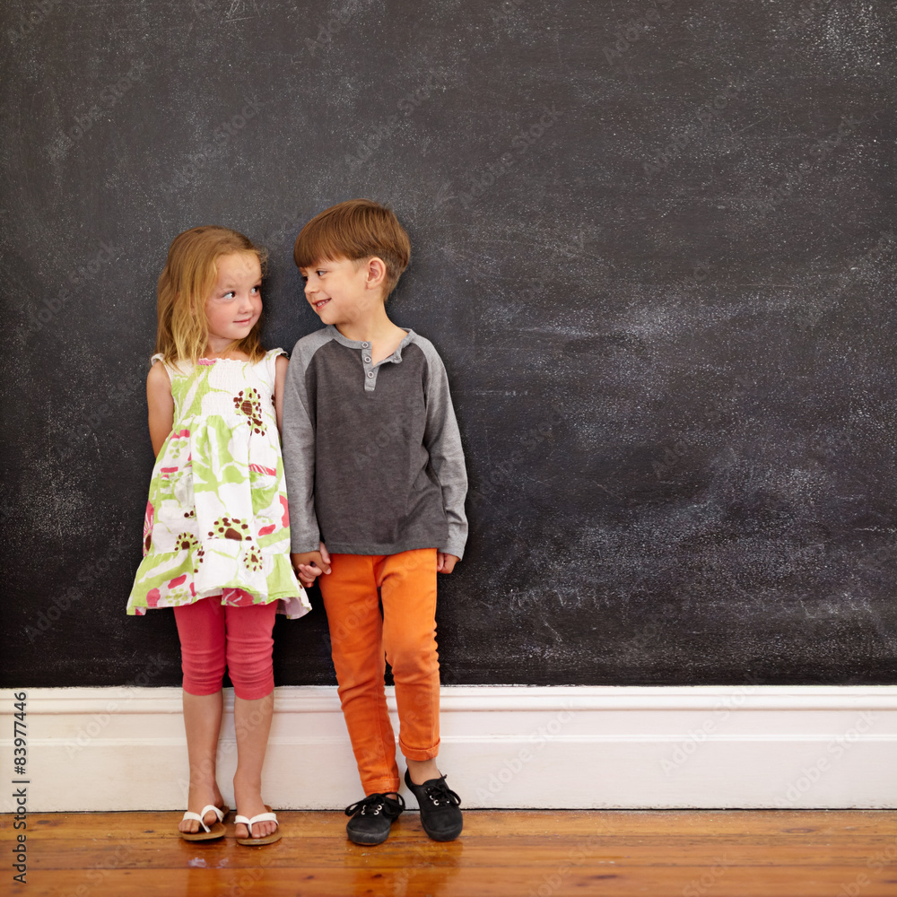 Little boy and girl standing in front of blackboard
