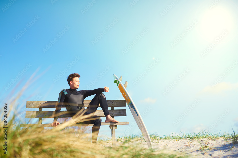 冲浪者在沙丘上的木长椅上放松