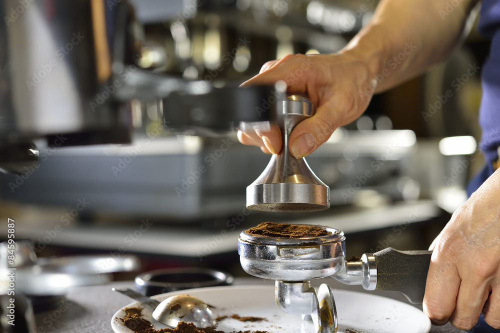 咖啡师用捣固器将研磨咖啡压入便携式过滤器