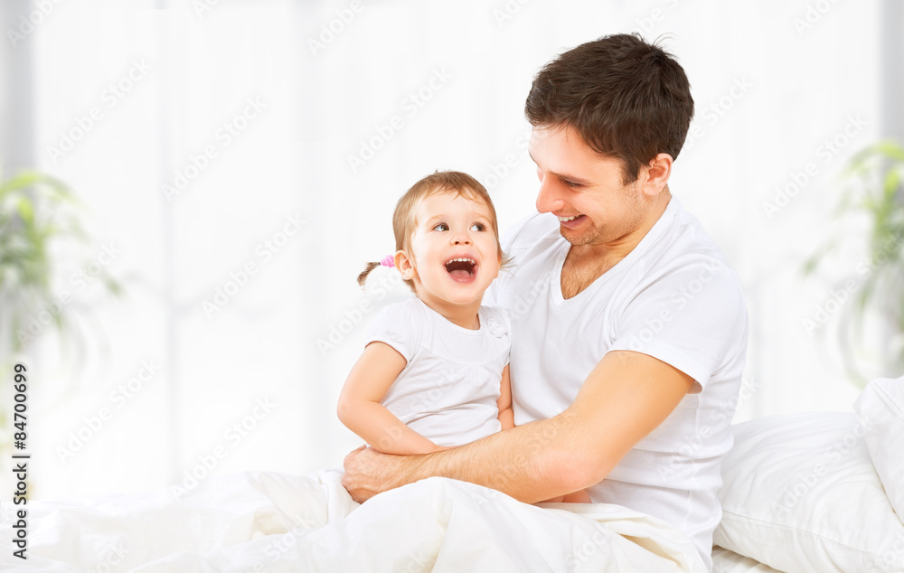 幸福的家庭父亲和宝贝女儿在床上玩耍