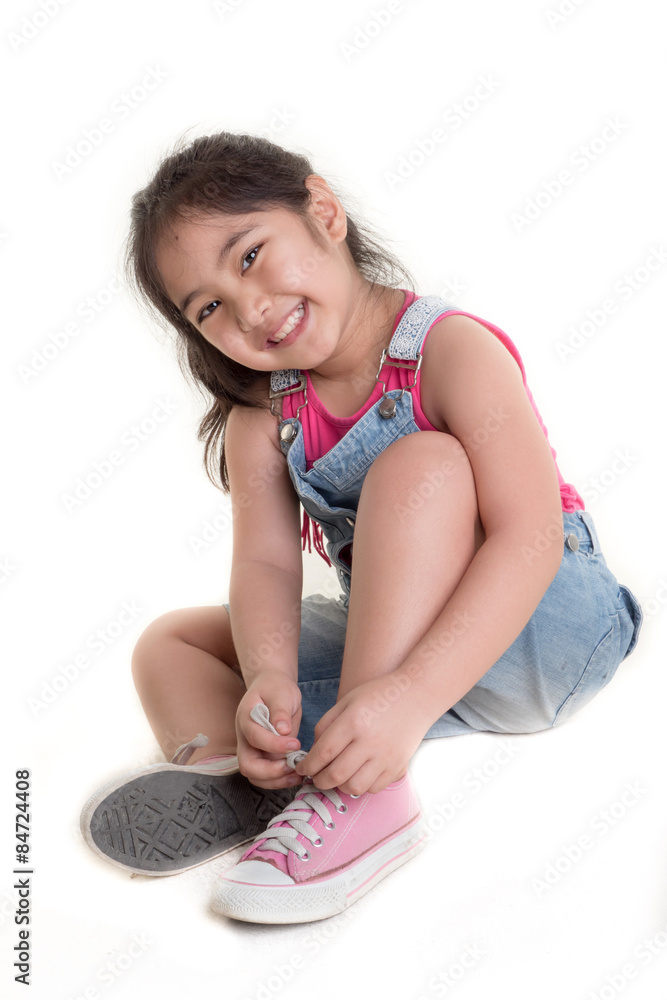 Little Asian Child practices to tying her shoes on isolated background