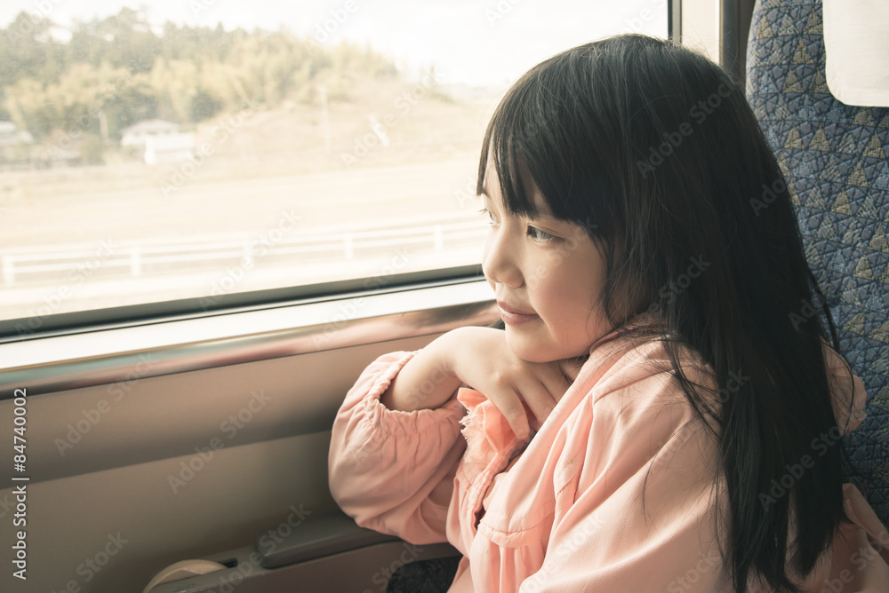 亚洲小女孩透过窗户看。她坐火车旅行
