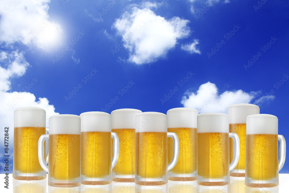 生ビール/真夏の青空に白い雲が浮かぶ背景にキンキンに冷えた生ビールを多数配置しています
