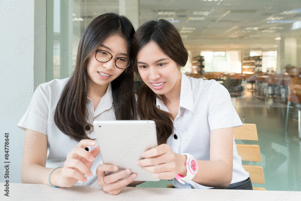 两名亚洲学生在带电子表格的教室里穿着制服