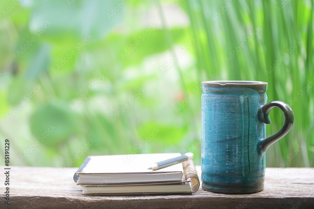 木桌上的笔记本和蓝色马克杯
