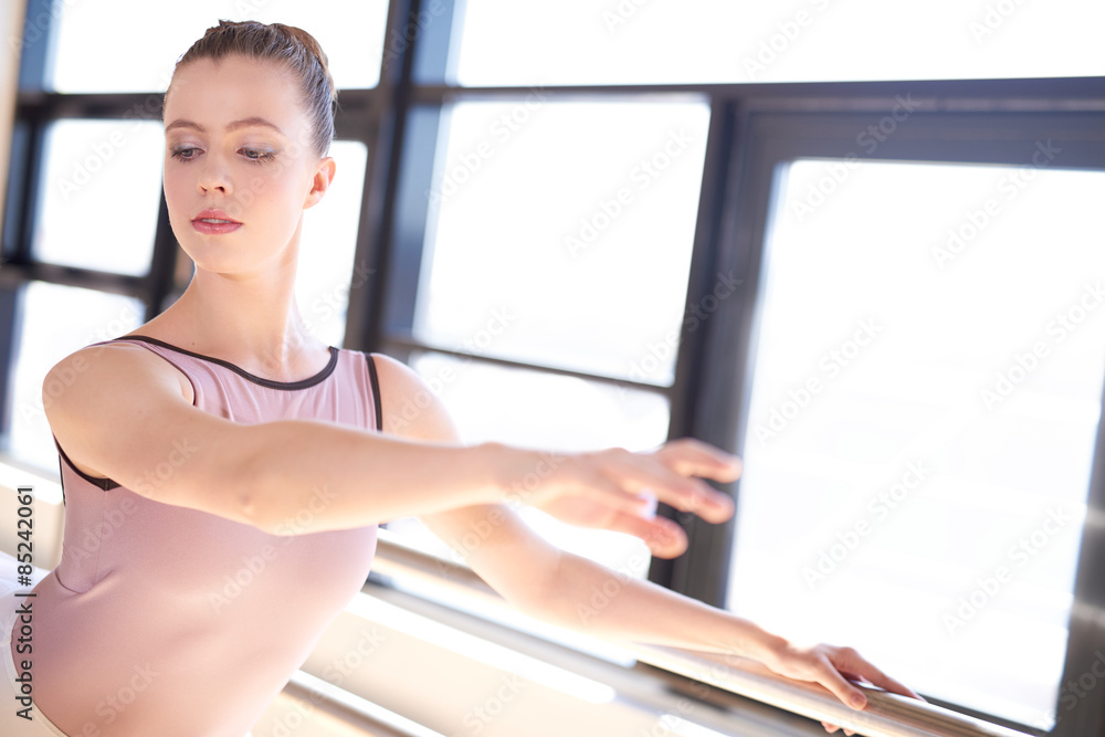 年轻的芭蕾舞演员在阳光明媚的工作室里热身