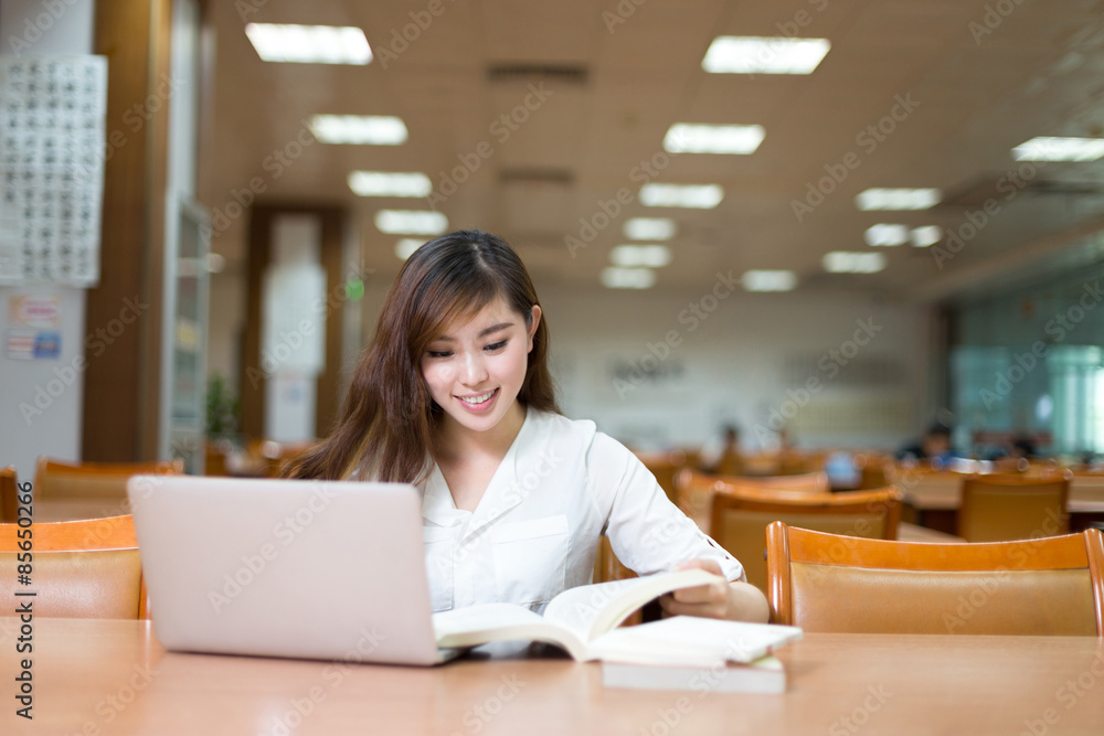 亚洲美女女学生在图书馆用笔记本电脑学习