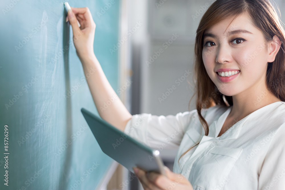 亚洲美女拿着平板电脑在黑板上写字