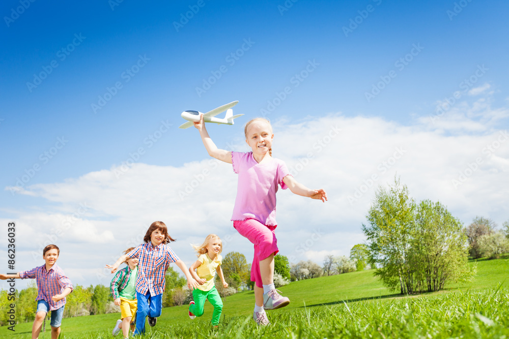 微笑的女孩拿着飞机玩具，孩子们在奔跑