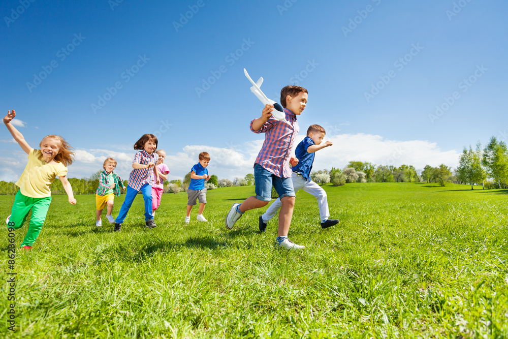 很多孩子在跑步，男孩拿着飞机玩具