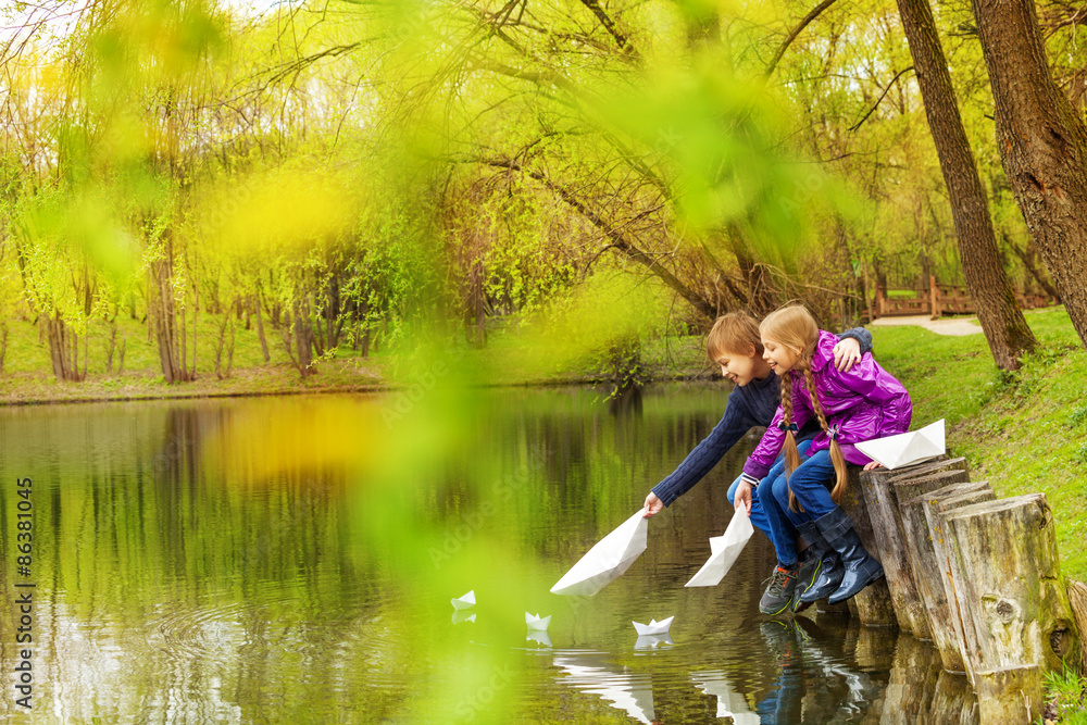 池塘边的男孩和女孩玩纸船