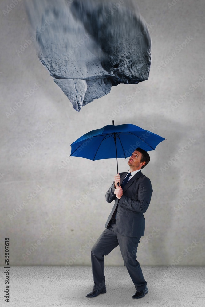 商人躲在蓝色雨伞下的合成图像