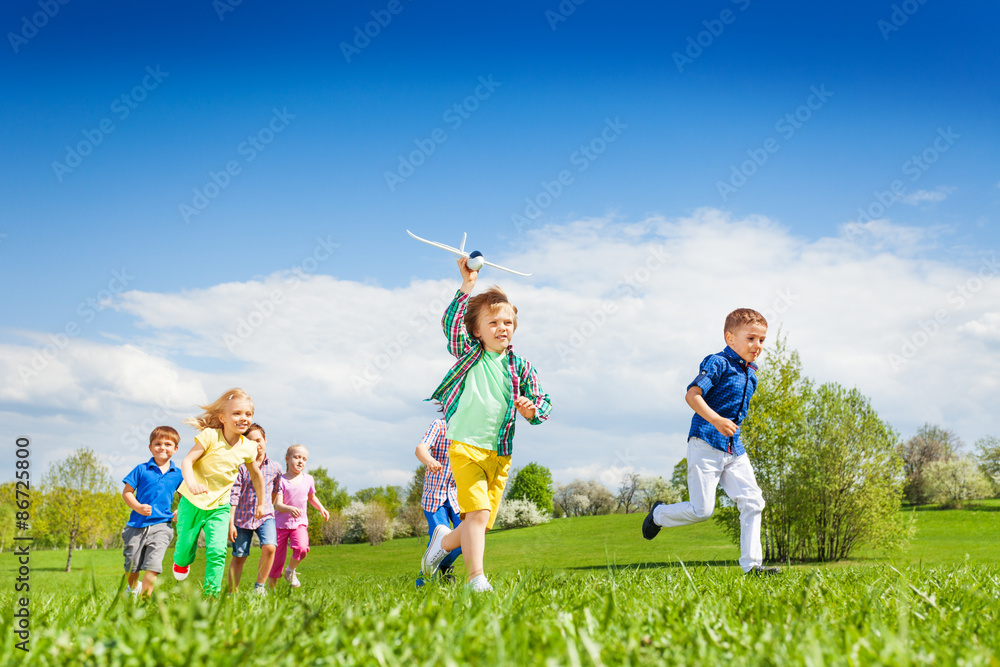Running boy with airplane toy and other children