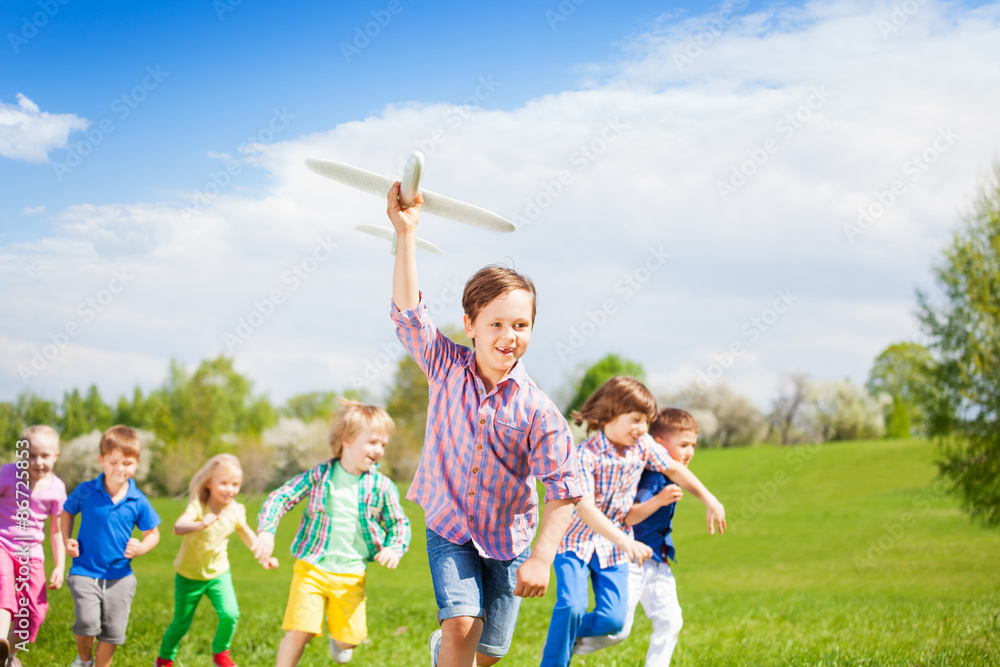 可爱的男孩和他的朋友带着大飞机玩具跑步
