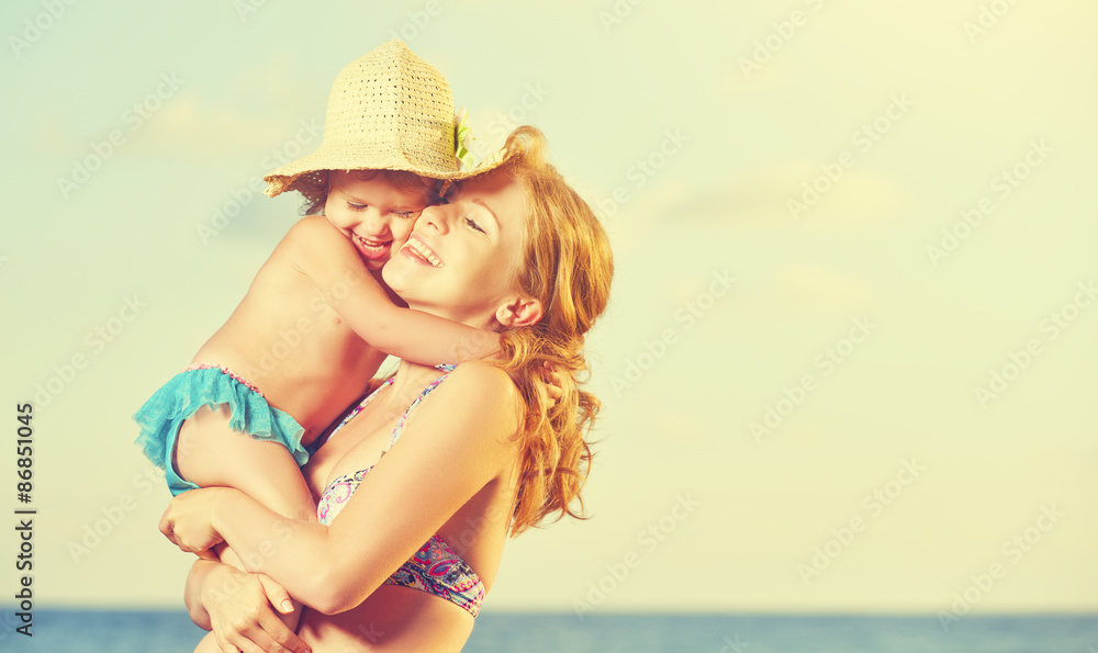 海滩上的幸福家庭。母亲和宝贝女儿拥抱