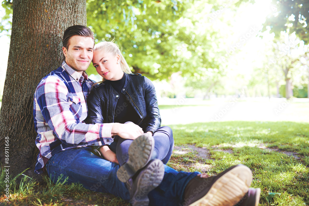 公园里的浪漫情侣坐在树旁