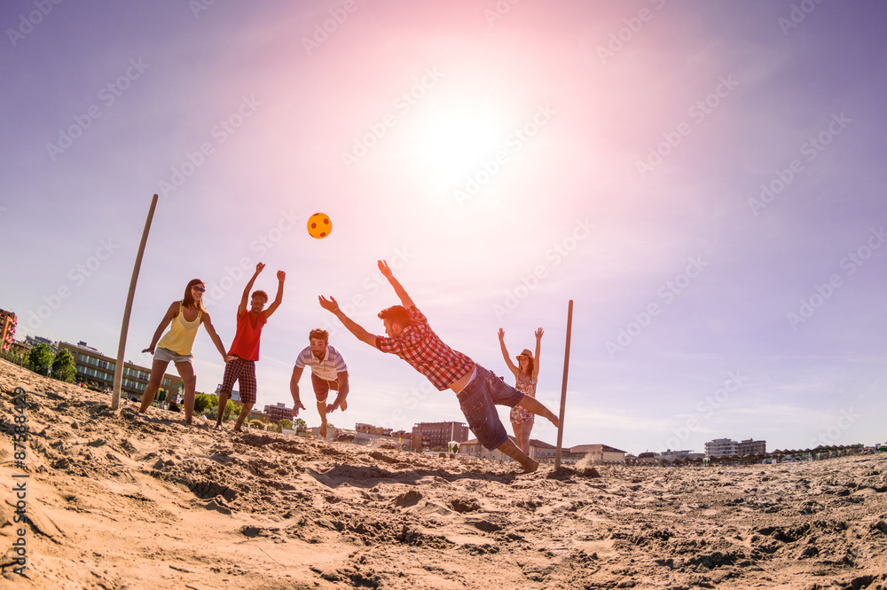 夏天快乐的多民族朋友在海滩上踢足球