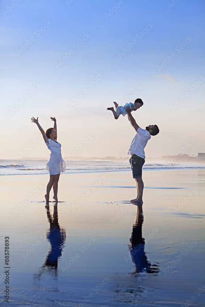 积极的家庭-父亲，带着小儿子的母亲在光滑的黑沙滩上尽情放松。健康